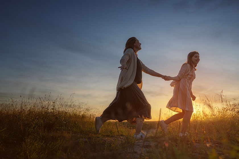 duas mulheres caminhando de mãos dadas em um campo